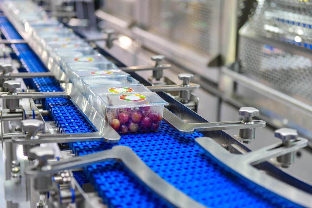 Image of fruit in containers going down a conveyor belt in an automated factory