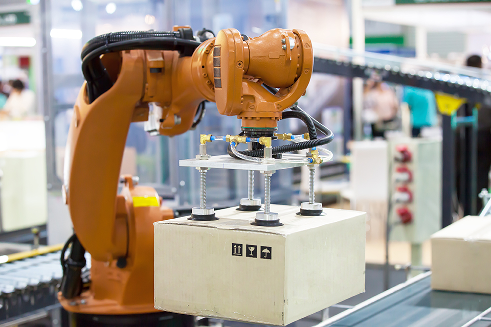 Image of a robotic arm in an automated factory moving a closed box